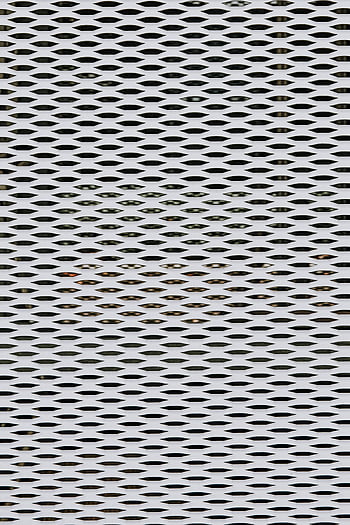 kovový plot, texturovaný povrch, díry, detail, kovová mřížka, geometrické vzory, fasáda, opakující se vzory, průmyslový design, architektonický detail, perforovaný kov