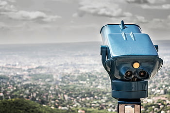 blue coin operated binocular, city view, daytime, coin-operated viewer, vast cityscape, cloudy sky, outdoor observation, public viewing device, scenic overlook, urban landscape, tourism attraction