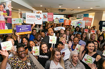 charity event, large group, people cheering, indoor gathering, signs, expressions of joy, lively celebration, community support, fundraising, nonprofit, volunteer event