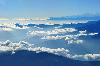 scenic view, clouds over mountains, blue sky, aerial view, stunning mountains, bright blue sky, mountain landscape, cloud formations, natural scenery, high altitude view, mountain peaks