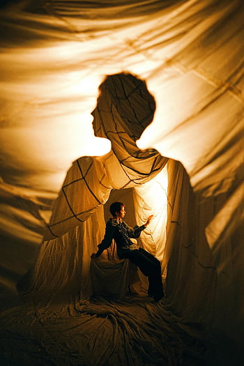 woman sitting, fabric posing, studio photography, creative lighting, fabric shadows, captivating scene, person interacting, artistic composition, studio setup, fabric art, shadow play