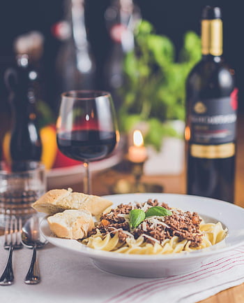pasta meal, red wine, restaurant setting, cooked food, delicious pasta, warm setting, dining table, food photography, meal presentation, wine pairing, bread accompaniment