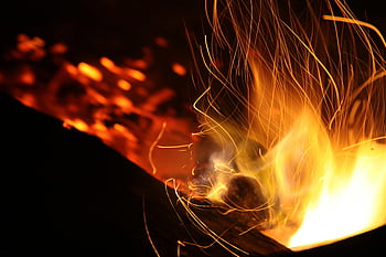 burning coal, dynamic flames, sparks, long exposure, warm atmosphere, night shot, fire photography, glowing embers, fiery sparks, coal fire, night flames
