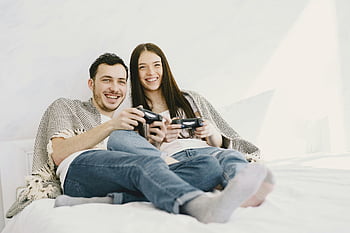 šťastný pár, Hraní herní konzole, ležet na posteli, Veselý pár, videohry, Útulná ložnice, herních řadičů, usmívající se pár, Vnitřní nastavení, neformální oblečení, pohodlné nastavení
