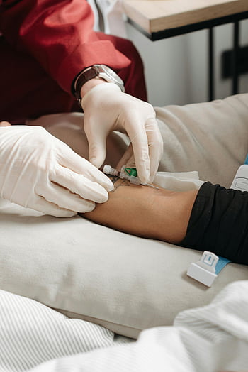 lékař zavádí jehlu, injekce do paže pacienta, lékařské prostředí, lékař v rukavicích, léčebného postupu, zdravotní péče, intravenózní injekce, trpělivá péče, lékařské ošetření, tetování paže, nemocniční postel