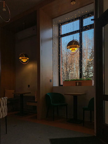 coffee shop interior, decorative hanging lamps, modern furniture, elegant lighting, warm café, inviting interior, window view, string lights, cozy seating, modern design, cafe ambiance