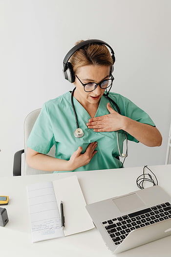 female doctor, video call, online consultation, scrubs, headphones, stethoscope, laptop, medical professional, telemedicine, healthcare worker, remote consultation