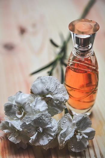 perfume bottle, glass bottle, white carnation, dew drops, wood surface, floral perfume, clear glass, perfume fragrance, beauty product, floral arrangement, natural perfume