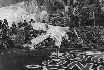 mies tanssii, tanssilattia, energinen breakdance-tanssija, vilkas graffiti, kaupunkikulttuuria, kadun suorituskyky, breakdance, graffiti-katu, urbaani tanssi, katutaide, tanssikulttuuri