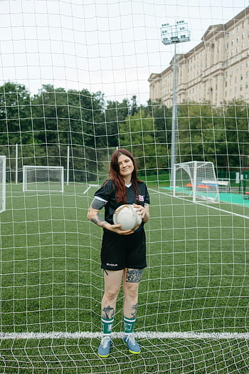 žena fotbalista, držící fotbalový míč, zelené pole, síť, sportovní hřiště, atletka, fotbalová uniforma, venkovní sporty, branková tyč, Atletická žena, fotbalový cíl
