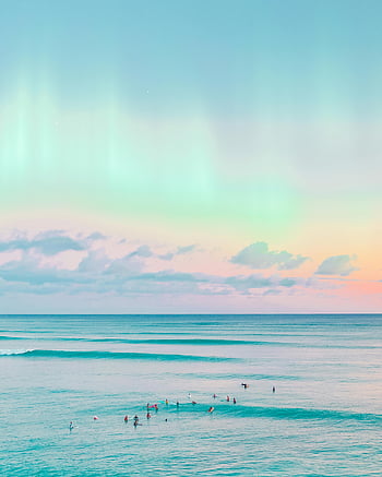 pink sky, turquoise water, ocean view, sunset, pastel skies, gentle waves, relaxation, tranquility, dreamy, surfers, beach scene