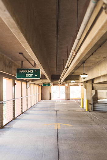 parking lot signage, well-lit parking garage, overhead signage, concrete structure, vacant parking garage, parking exit sign, parking garage interior, parking garage lighting, parking garage design, parking garage layout, parking garage signage