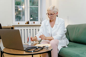 female doctor, online consultation, elderly doctor, home office, telemedicine, medical professional, laptop, stethoscope, healthcare, remote consultation, telehealth