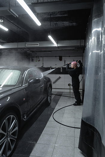 woman washing car, pressure washer, black car, indoor garage, car cleaning, worker, car wash, garage setting, vehicle maintenance, auto care, car detailing