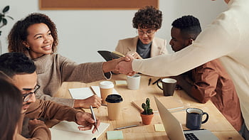 woman smiling, shaking hands, colleagues collaborating, business meeting, indoor setting, professional interaction, team collaboration, office environment, workplace interaction, group discussion, smiling colleagues