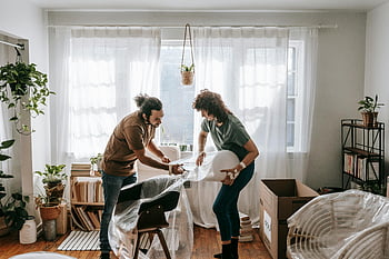 couple, bubble wrap, chairs, packing furniture, modern living room, bright room, moving day, home decor, indoor plants, cardboard boxes, joyfully packing