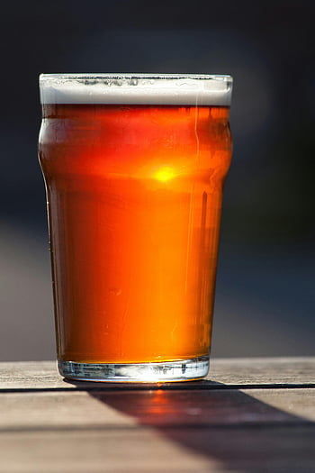 Amber Ale, jasne szkło do picia, stół na zewnątrz, światło słoneczne, orzeźwiający kufel, czerwony napój, Burszkowe piwo, szklanka piwa, ustawienie na zewnątrz, odbicie światła słonecznego