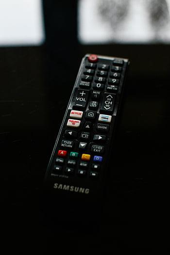 Samsung TV remote, close-up shot, detailed buttons, dark surface, remote control, Netflix button, Rakuten TV, Amazon video, guide button, exit button, volume control