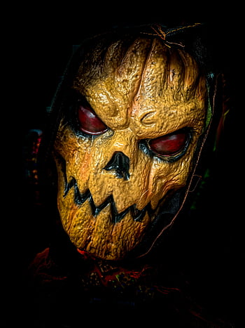 Halloween mask, spooky pumpkin mask, glowing red eyes, horror theme, close-up, scary mask, Halloween costume, pumpkin face, eerie, jack-o-lantern mask, spooky costume