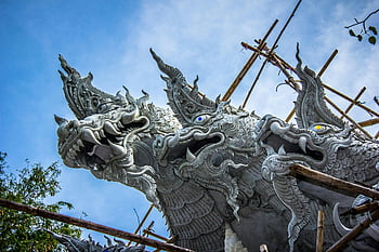 dragon sculpture, Wat Phra Kaew Temple, Amphoe Mueang Ubon Ratchathani, Thailand, scaffolding, bright sky, detailed dragon, temple architecture, cultural landmark, traditional art, outdoor sculpture