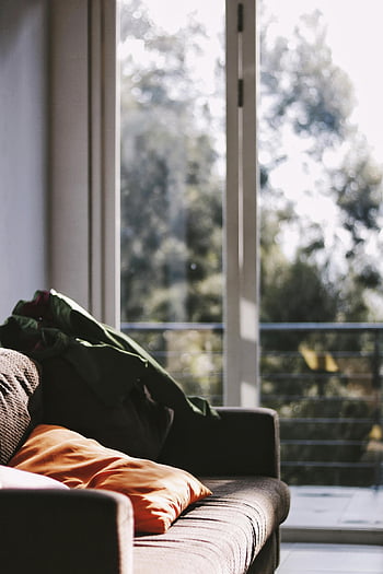 brun soffa, klart glaspaneldörr, mysigt vardagsrum, solljusströmning, skjutdörrar, mjuka kuddar, soffa, inomhusinredning, naturligt ljus, heminredning, bekväma sittplatser