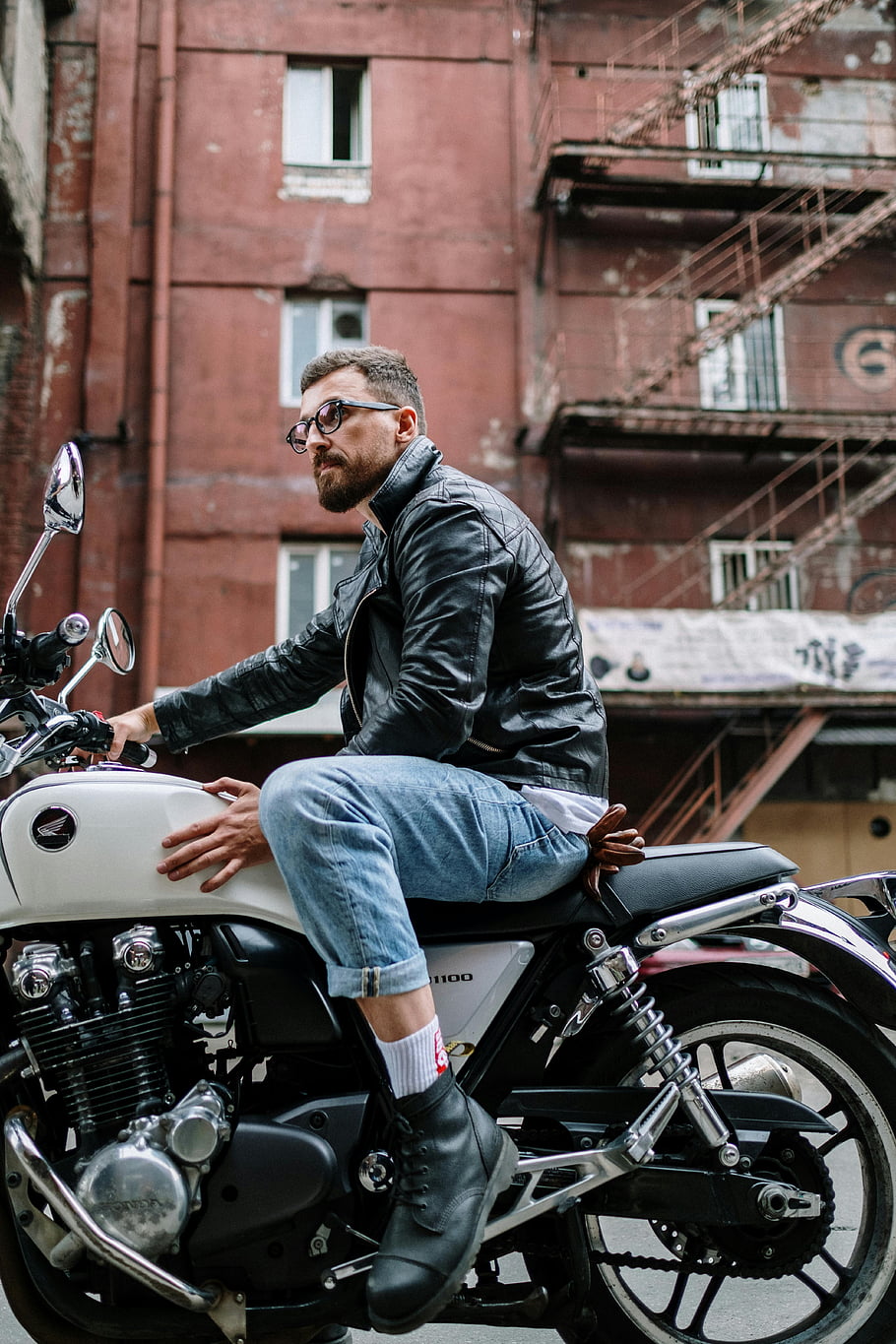 man in black leather jacket, white motorcycle, city alleyway, industrial backdrop, urban setting, motorcycle rider, leather jacket, white bike, cityscape, industrial building, urban lifestyle