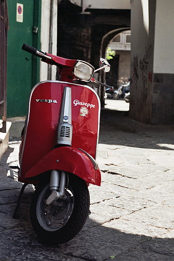 red Vespa scooter, Vespa Giuseppe, charming street, Napoli Italy, close-up Vespa, iconic red Vespa, parked Vespa, cobblestone street, Italian scooter, vintage Vespa, street scene