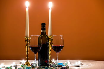 candlelit dinner, red wine, elegant glassware, luxury dining, wine glasses, wine bottle, lighted candles, cozy setting, romantic dinner, dining experience, elegant table setting
