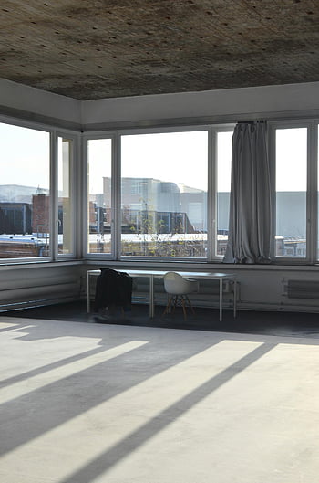 spacious studio, table at window, bright loft space, large windows, cityscape view, creative design, modern empty loft, studio with table, empty loft space, studio with windows, modern studio space