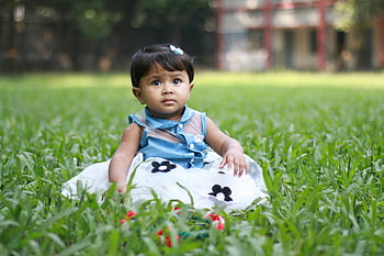 baby sitting on grass, cute baby girl, green grass field, blue dress, outdoors daytime, baby outdoors, baby in dress, baby on grass, baby girl, baby photography, baby in nature