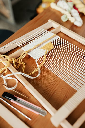 hand loom, weaving process, yarn, workshop, close-up, craft, textile, DIY, wooden loom, weaving tools, handmade