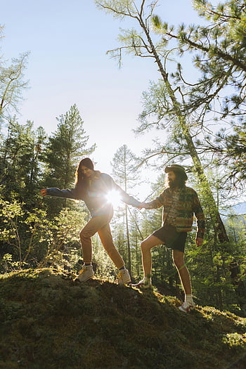 couple hiking, forest trail, sunlight streaming, trees, green grass, man and woman, outdoor adventure, nature walk, forest scenery, hiking couple, forest hike