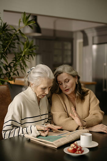 women solving crossword, senior women, cozy home setting, dining table, newspaper crossword puzzle, enjoying together, multi-generational, indoor activity, casual conversation, relaxed atmosphere, home leisure