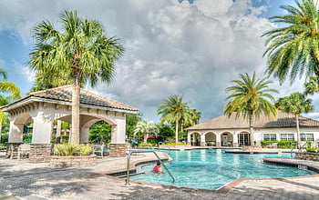 White Concrete Gazebo, tropical resort, poolside scene, palm trees, inviting water, cloudy sky, resort pool, outdoor relaxation, vacation destination, tropical getaway, poolside gazebo