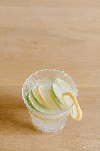 citrusinfuserad dryck, kalkskivor, citronskivor, klart glas, träbord, cocktail, glas med cocktail, citron med lime, citrus dryck, uppfriskande drink, dukning