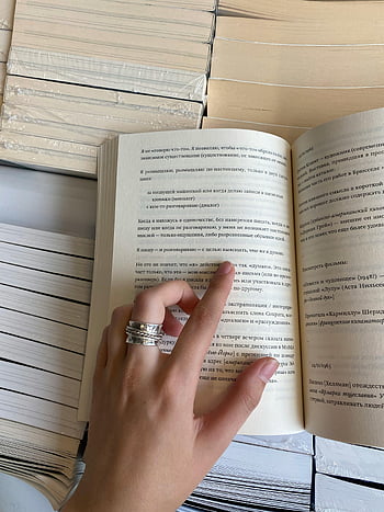 指している女性、 本の中の行、 本を開く、 積み上げ書籍、 屋内設定、 テキストポインティング、 読むジェスチャー、 本の背景、 テキストに指を置く、 本棚、 屋内読書
