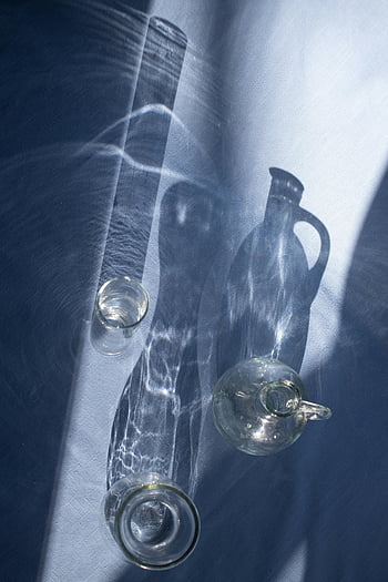 transparent glassware, abstract shadows, sunlight, textile, glass vases, creative arrangement, glass bottles, shadow play, still life, artistic photography, home decor