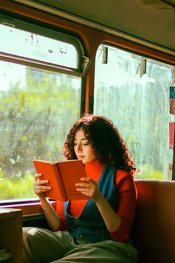 bruna che legge un libro, viaggio in autobus, luce naturale, giovane donna, lettura del libro, interno di autobus, lettura di viaggio, Abbigliamento casual, vista della finestra, trasporto pubblico, Lettura rilassata