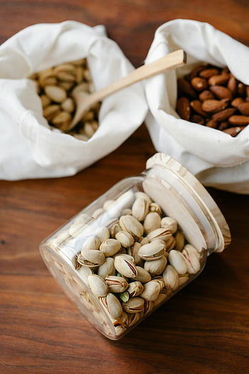 eco friendly package, sustainable packaging, nuts, glass jar, reusable cloth bags, wooden table, pistachios, almonds, eco-friendly, sustainable, glass container