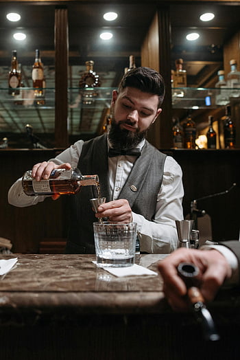 barista, preparare una bevanda alcolica, whisky, bar elegante, bottiglie di liquore, barista barbuto, versare whisky, bancone da bar, Ambiente del bar, Preparazione del cocktail