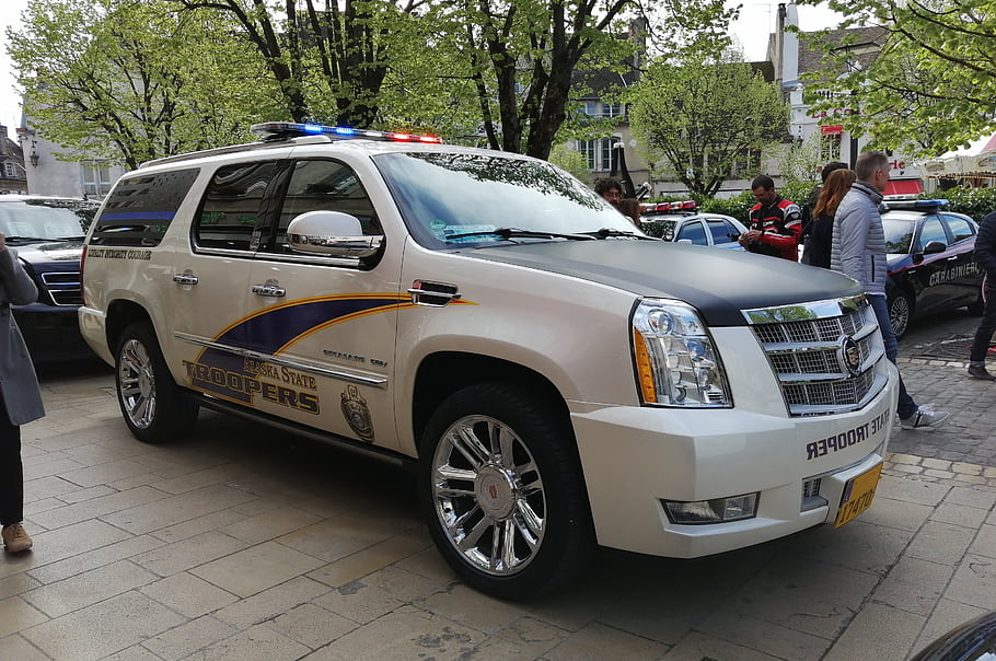 Cadillac Escalade, Alaska State Troopers, police car, law enforcement, vehicle, emergency lights, public safety, street scene, people, urban setting, yellow license plate
