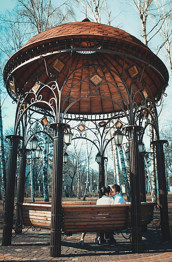koppel zoenen, metalen tuinhuisje, romantisch moment, parket, Prachtig ontworpen prieel, buitenspaar, romantisch koppel, Park Gazebo, Paren in Gazebo, romantische scène, bank in het park
