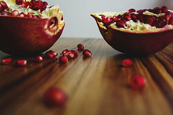pomegranate, sliced fruits, seeds, vibrant colors, wooden table, shallow focus, fresh pomegranate, cut pomegranate, fruit seeds, healthy food, natural colors