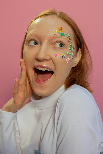 surprised lady, animal stickers, open mouth, expressive woman, playful face stickers, pink background, showcases joy, individuality, face decorations, fun expression, colorful stickers