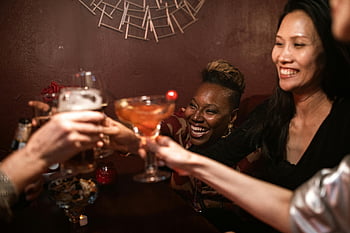 friends toasting, drinks, cozy indoor bar, cheerful group, toasting drinks, indoor bar setting, social gathering, friends celebrating, bar atmosphere, group celebration, cocktails