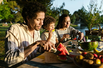 perheen piknik, päiväsaikaan piknik, ulkona oleva piknik, iloinen perhe, nauttien vesimelonia, aurinkoinen päivän piknik, piknik ulkona, perhe nauttii piknikistä, vesimelonipiknik, piknik-pöytä, perheen yhteinen piknik
