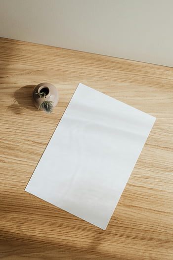 Lege papieren blad, houten tafel, minimalistische opstelling, blanco vel papier, keramische vaas, houten bureau, eenvoudige samenstelling, schoon ontwerp, bureau, werkruimte, natuurlijk licht
