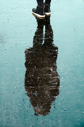 shadow, person, water, daytime, artistic reflection, black boots, puddle, rain, outdoor scene, wet surface, human silhouette