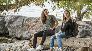 teenage girls, sitting on log, by water, casual day outdoors, smiling girls, outdoor photo, daytime photo, nature setting, two girls, log by water, enjoying outdoors