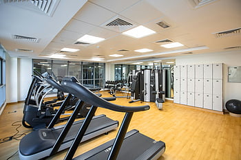 interiér tělocvičny, běžecké pásy, fitness stroje, skříňky, Prostorná tělocvična, cvičební zařízení, černá a šedá, tělocvična, skříňky v tělocvičně, prostor pro tělocvičnu, fitness centrum